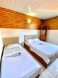 a bedroom with two beds and a brick wall at Felicità Praia Hotel in Fortaleza