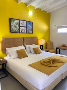 a bedroom with a large white bed with yellow walls at Hotel Aromax del Campestre in Medellín