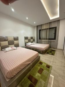 a bedroom with two beds and two rugs at Luxueux S+2 Menzah5 in Ariana