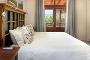 a bedroom with a large white bed with a window at Aan de Heuvel Self-Catering Cottages in Swellendam