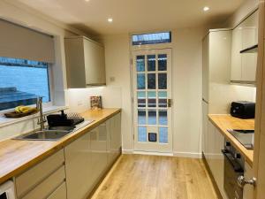 a kitchen with white cabinets and a sink and a window at Newly Refurbished City Centre House With Parking in Exeter +14 photos