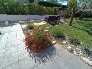 un jardin avec un banc et des fleurs rouges dans l'établissement Villa les Doms, à Mazan