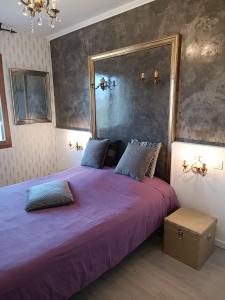 a bedroom with a purple bed with a large mirror at Villa les Doms in Mazan