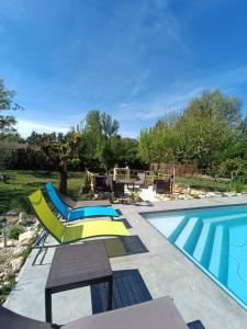 a swimming pool with two lounge chairs and a table at Villa les Doms in Mazan