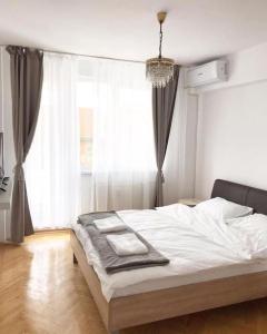 um quarto com uma cama com lençóis brancos e uma janela em Joy City Stay Victoriei 7E-30 2 em Timisoara