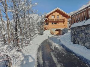 uma estrada coberta de neve em frente a uma cabana de madeira em Les Cabris em Pelvoux