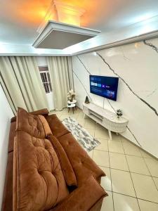 a living room with a couch and a flat screen tv at Apê a 4 min da Basílica in Aparecida