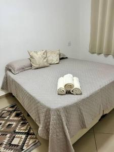 ein Bett mit Handtüchern und Kissen darauf in der Unterkunft Apê a 4 min da Basílica in Aparecida