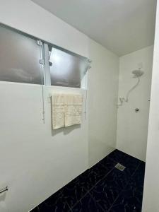 ein weißes Bad mit einem an der Wand hängenden Handtuch in der Unterkunft Apê a 4 min da Basílica in Aparecida