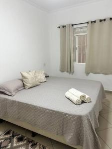 een witte slaapkamer met een bed met handdoeken erop bij Apê a 4 min da Basílica in Aparecida
