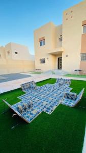 dwa parasole siedzące na trawie przed budynkiem w obiekcie Palm Villa w mieście Al-Ula