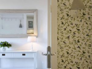 a bathroom with a mirror and a flowery wallpaper at Holiday apartment Domstag in Kronsgaard