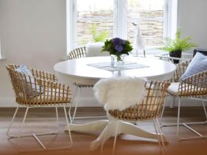 KronsgaardにあるHoliday apartment Domstagのダイニングルーム(白いテーブル、籐の椅子付)