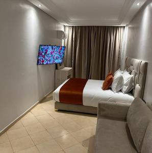 1 dormitorio con 1 cama, TV y sofá en Residence La Perle de l'Atlas Marrakech, en Marrakech