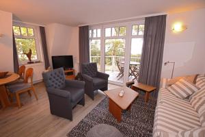 ein Wohnzimmer mit einem Sofa, Stühlen und einem Tisch in der Unterkunft Strandvilla Drei Mäderl Haus in Boltenhagen