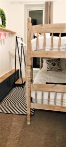 Ce lit superposé en bois se trouve dans un dortoir doté d'un tapis. dans l'établissement The Captain's Lodge Looe, à Looe