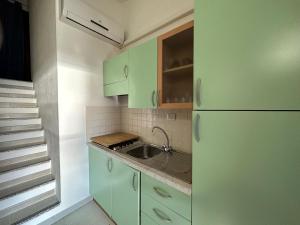 a kitchen with green cabinets and a sink at Domus Tom Apartment with sea view Villasimius in Simius