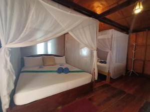 ジュム島にあるジャングル ヒル ビーチ バンガローのベッドルーム(天蓋付き白いベッド1台付)
