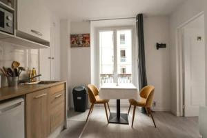 een keuken met een tafel en stoelen en een raam bij Appartement 4 personnes Oberkampf in Parijs