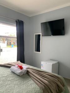 a bedroom with a bed with a flat screen tv on the wall at Pousada Tia Alice in Penha