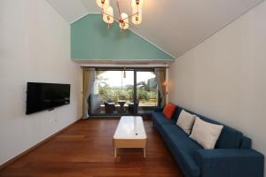 un soggiorno con divano blu e TV di Park Art Villas a Buyeo