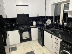 een keuken met witte kasten en zwarte apparaten bij 3BD Sanctuary in Beeston, Nottinghamshire in Beeston