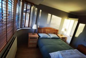 een slaapkamer met een bed, een nachtkastje en ramen bij ANAND HOUSE in Harrow