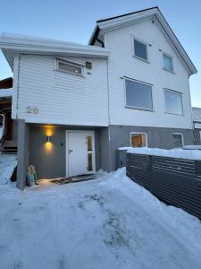 a white house with a garage in the snow at Sentralt plassert leilighet ved Sherpatrappen in Tromsø