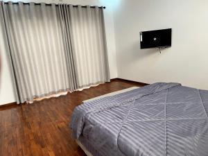 1 dormitorio con 1 cama y TV de pantalla plana en Txumas, en Maputo