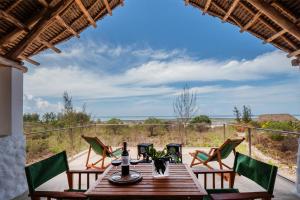 uma mesa de madeira com cadeiras numa varanda com vista para o oceano em Amani Villas Nature Retreat em Michamvi