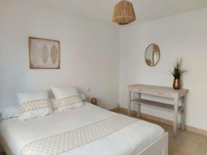 a white bedroom with a bed and a table at Les Arènes - Superbe 2 chambres in Nîmes