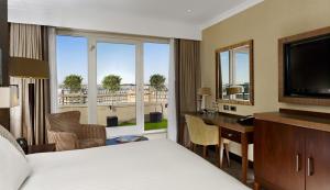 um quarto de hotel com uma cama, uma secretária e uma televisão em DoubleTree by Hilton London Victoria em Londres
