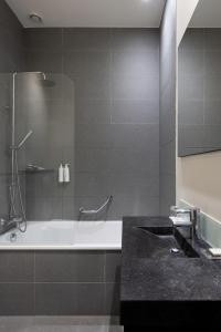 a bathroom with a bath tub and a sink at Catalonia Vondel Amsterdam in Amsterdam +51 photos