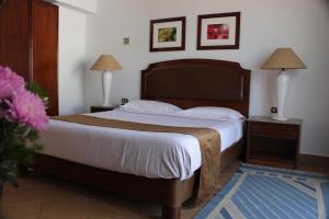 ein Schlafzimmer mit einem großen Bett, zwei Lampen und einer Vase aus Blumen in der Unterkunft Marlin Inn Azur Resort in Hurghada