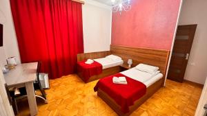 een kamer met 2 bedden en een rood gordijn bij Elross Hotel in Jerevan