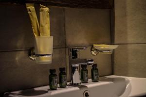 Hotel Misty Mountain في كازباجي: مغسلة الحمام عليها اربع زجاجات