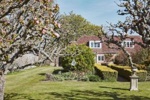 a house with a garden with flowers and trees at Filbert cottage, log fire and tennis court in Rolvenden