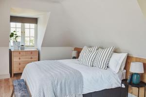 a bedroom with a bed and a dresser with a window at Filbert cottage, log fire and tennis court in Rolvenden