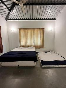 two beds in a room with a window at Mhaske Farms in Pune