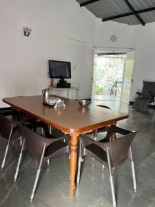 a wooden table and chairs in a room with a television at Mhaske Farms in Pune