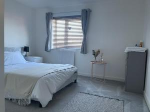 a white bedroom with a bed and a window at Walsall New Large House with Garden in Pelsall
