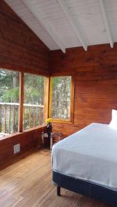 1 dormitorio con 1 cama en una habitación con ventanas en Espacio Aquarel Patagonia en El Bolsón