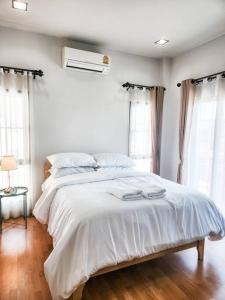 a bedroom with a large bed with white sheets at Simple & Cozy Home in prime location. Chiang Mai in Chiang Mai