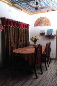 un comedor con una mesa con sillas y un jarrón de flores en DreamCatcher Residency, en Kochi