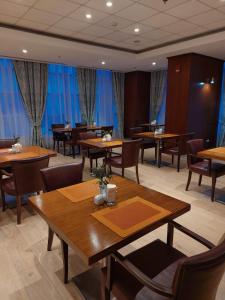 een restaurant met houten tafels en stoelen en blauwe gordijnen bij Atyrau Executive Apartments in Atıraw
