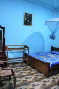 a blue room with a bed and a chair at ගයාන් ගෙස්ට් කතරගම in Kataragama