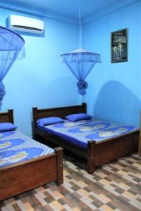 two beds in a room with blue walls at ගයාන් ගෙස්ට් කතරගම in Kataragama