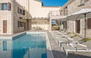 a pool with lounge chairs and an umbrella next to a building at Amazing Home In Sveti Lovrec With Outdoor Swimming Pool in Vošteni
