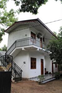 a small white house with a balcony on it at ගයාන් ගෙස්ට් කතරගම in Kataragama