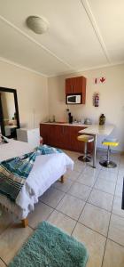 ein Schlafzimmer mit einem Bett und einem Tisch sowie eine Küche in der Unterkunft BluePalms Guesthouse in Swakopmund